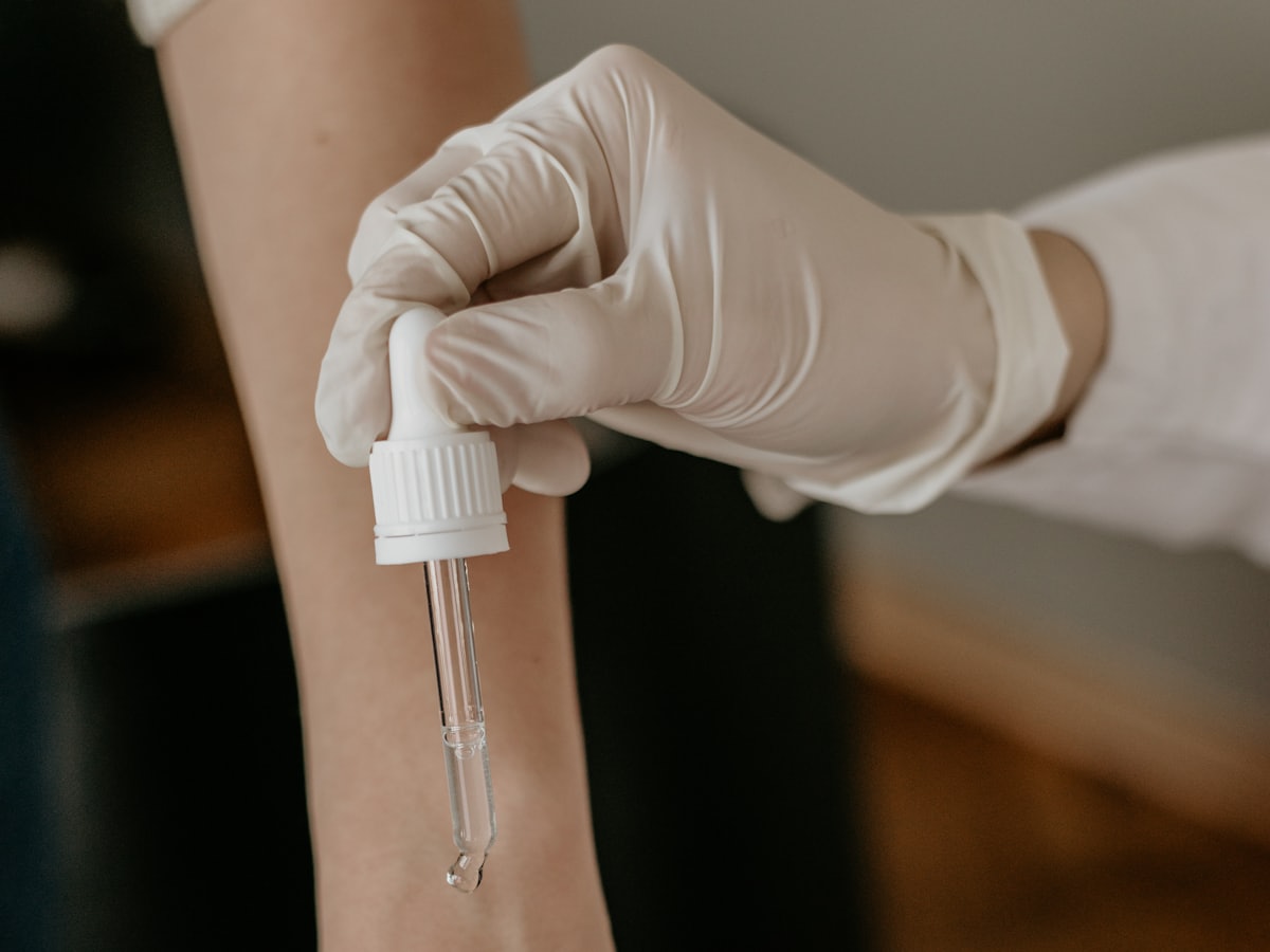 Gloved hands holding a dropper bottle during a treatment